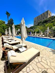 una fila di sedie a sdraio con ombrelloni accanto alla piscina di Bellapais Gardens a Kyrenia