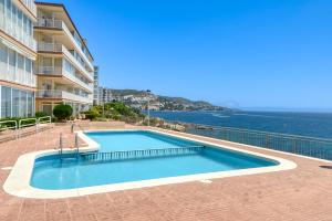 a swimming pool next to a building and the ocean at Ático Crucero Suite VIP in Roses