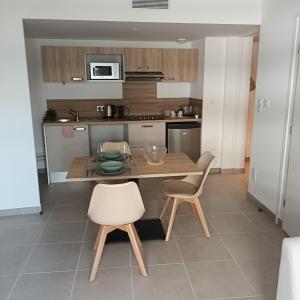 a kitchen with a wooden table and two chairs at Cosy Diem Cap d'Agde in Cap d'Agde