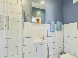 ein weiß gefliestes Badezimmer mit Waschbecken und Spiegel in der Unterkunft Seaside Cottage, Moments from Ryde's Golden Sands, Sleeps 4 in Ryde + 19 Fotos