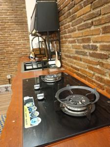 a table with a stove and a tv on a brick wall at Villa Sasandu Termanu in Gadog