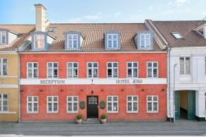 Hotel Ærø في سفينبورغ: مبنى من الطوب الأحمر كبير مع نوافذ بيضاء