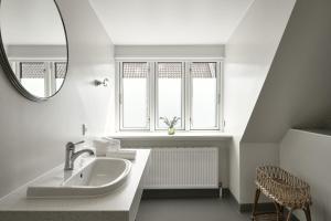 ein weißes Badezimmer mit Waschbecken und Spiegel in der Unterkunft Hotel Ærø in Svendborg + 234 Fotos