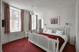 ein Schlafzimmer mit einem weißen Bett und zwei Fenstern in der Unterkunft Hotel Ærø in Svendborg