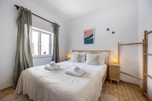 Un dormitorio con una gran cama blanca con toallas. en Casa Ana Mar, en Vila do Bispo