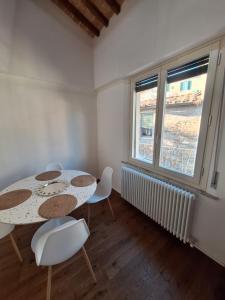 a dining room with a table and chairs and two windows at il "Terrazzino" nel cuore di Siena in Siena