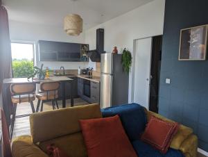a living room with a couch and a kitchen at la Pléiade in Pont-Hébert