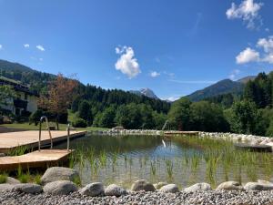 a lake with a wooden dock in the middle at Gasthof Skirast in Kirchberg in Tirol