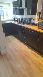 a kitchen with black cabinets and a wooden floor at Paul's Place in Longbridge