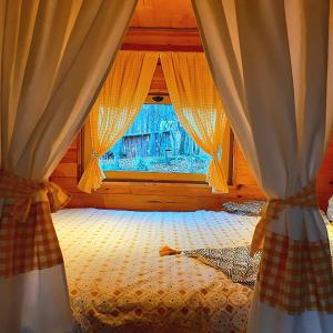 a bedroom with a bed with curtains and a window at Roulotte avec piscine la jonquille in Valgorge +10 photos
