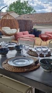 une table avec des assiettes et des verres à vin dessus dans l'établissement Magnifique maison provençale haut standing avec piscine, jardins, garages fermés, à Sablet