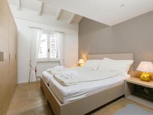 een slaapkamer met een bed met witte lakens en een raam bij Apartment Residenza Chesa Margun 36-3 by Interhome in Surlej