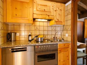 a kitchen with a stainless steel stove and wooden cabinets at Apartment Residenza Chesa Margun 15-3 by Interhome in Surlej