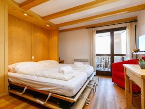 a bedroom with a bed and a red couch at Apartment Residenza Chesa Margun 78-4 by Interhome in Surlej