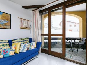a living room with a blue couch and a table at Apartment Residenza Chesa Margun 33-5 by Interhome in Surlej +20 photos
