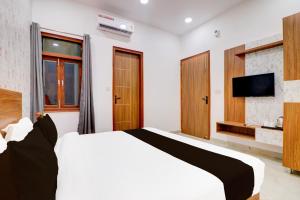 1 dormitorio con 1 cama blanca y TV en Collection O HOTEL NIRVAN, en Delhi
