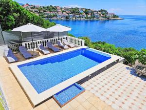 a swimming pool with chairs and a view of the water at Apartment Snježana-1 by Interhome in Zavalatica