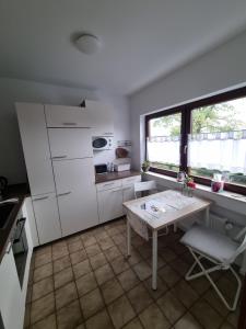 a kitchen with white cabinets and a table and window at Miu's Ferienwohnung in Alpirsbach