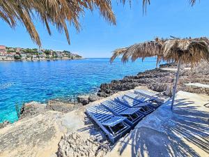 two lounge chairs under a straw umbrella on a beach at Apartment Snježana-3 by Interhome in Zavalatica