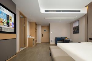 a hotel room with a bed and a flat screen tv at Atour Hotel Changhong Avenue in Jiujiang