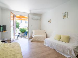 Sala de estar blanca con sofá y silla en Apartment Le Lido-3 by Interhome, en Les Lecques