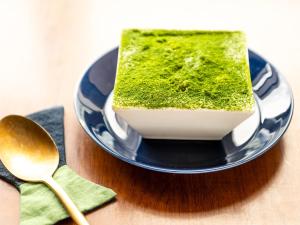 a piece of green cake on a plate with a spoon at Mitsui Garden Hotel Sendai in Sendai