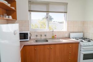 cocina con fregadero, microondas y ventana en Apartment 25 Burswood, en Perth