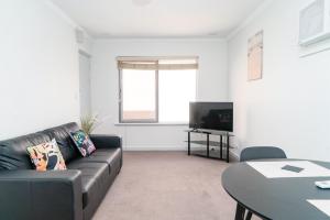 Una sala de estar con un sofá negro y una mesa. en Apartment 25 Burswood, en Perth