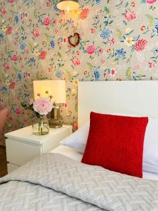 een slaapkamer met een rood kussen en bloemenbehang bij Pension22 in Meißen