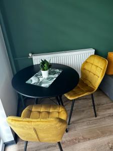 a black table with yellow chairs and a plant on it at Apartament Sulików in Sulików
