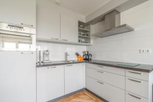 a white kitchen with white cabinets and stainless steel appliances at Appartementencomplex Juliana 146 in De Koog