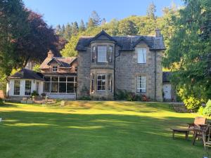 a large stone house with a grass yard at Lubnaig Guest House in Callander