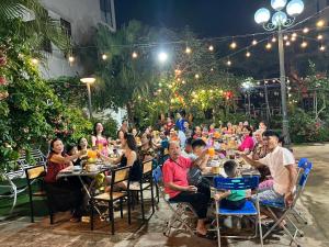 a group of people sitting at tables in an outdoor restaurant at Lux Hotel FLC Sầm Sơn in Sầm Sơn