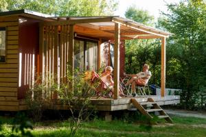 twee mensen zitten op een veranda van een klein huisje bij Huttopia Saumur in Saumur