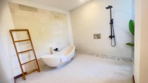 a bathroom with a white tub and a shower at Kubu Dimel Suites and Villas Resort in Nusa Dua