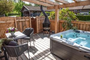 a hot tub on a deck with a grill at Chalet Waldzeit in Zachenberg