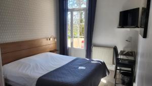 a bedroom with a bed and a window at Logis Hotels - Au Colombier du Touron in Brax