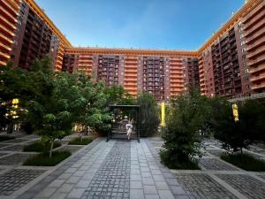 a person sitting on a bench in front of a large building at Апартаменты в ЖК Green Plaza с джакузи in Aktau