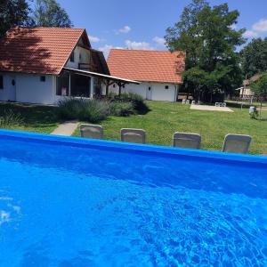a blue swimming pool in front of a house at Mirella rooms in Palić