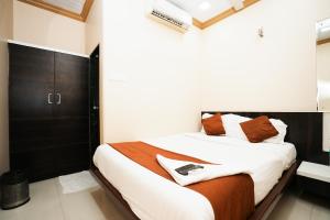 Hotel Airport Metro Near Chhatrapati Shivaji International Airport في مومباي: غرفة نوم بسرير وملاءات بيضاء ومخدات برتقالية