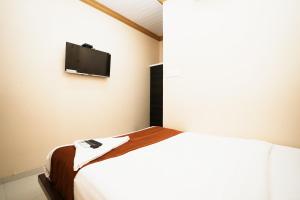 Hotel Airport Metro Near Chhatrapati Shivaji International Airport في مومباي: غرفة نوم مع سرير وتلفزيون على الحائط