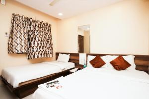 Cette chambre comprend 2 lits et un miroir. dans l'établissement Hotel Airport Metro Near Chhatrapati Shivaji International Airport, à Mumbai