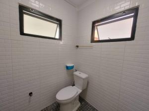 a bathroom with a white toilet and two windows at 辉煌夜市 4房泳池花园别墅 订4日提供免费接机 in Ban Na Song