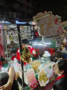 a woman standing in front of a food stand at 辉煌夜市 4房泳池花园别墅 订4日提供免费接机 in Ban Na Song