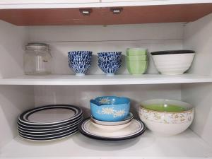 a shelf filled with plates and bowls and bowls at 辉煌夜市 4房泳池花园别墅 订4日提供免费接机 in Ban Na Song