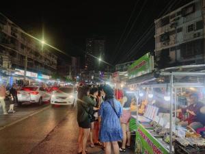 a group of people standing around a food stand on a city street at 辉煌夜市 4房泳池花园别墅 订4日提供免费接机 in Ban Na Song