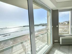 a view of the beach from a room with windows at Bel appartement en front de mer avec balcon, parking et équipements modernes - FR-1-361-327 in Granville