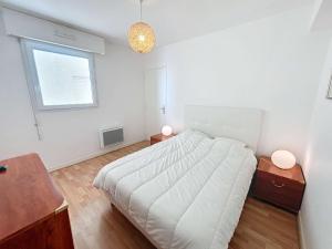 a white bedroom with a bed and two night stands at Bel appartement en front de mer avec balcon, parking et équipements modernes - FR-1-361-327 in Granville