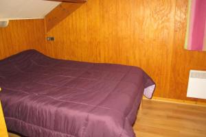 a bedroom with a purple bed with wooden walls at Chalets les tutes de la Vernière in Auzat