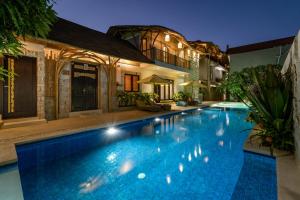 a swimming pool in front of a house at Bali Sunshine Nusa Dua in Nusa Dua